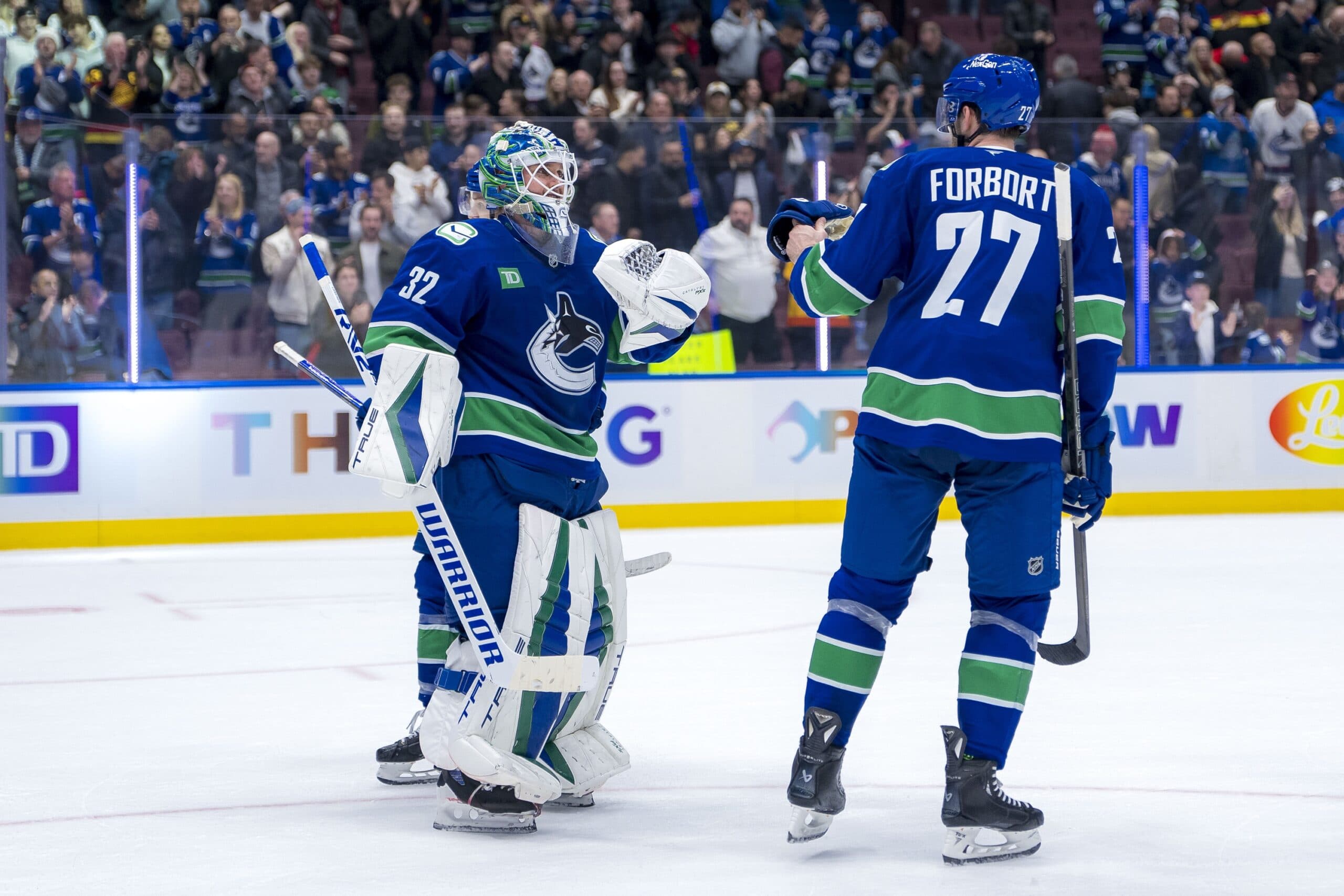 Vancouver Canucks goalie Kevin Lankinen (32) and defenseman Derek Forbort (27) celebrate the victory against the Florida Panthers at Rogers Arena.