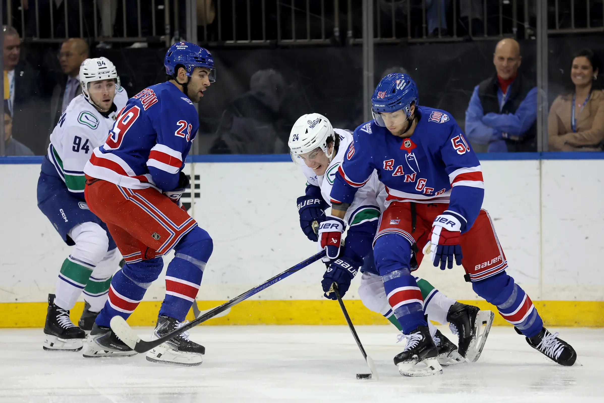 Vancouver Canucks center Linus Karlsson (94) and defenseman Zeev Buium (24) fight for the puck against New York Rangers defenseman Matthew Robertson (29) and left wing Will Cuylle (50) during the first period at Madison Square Garden.